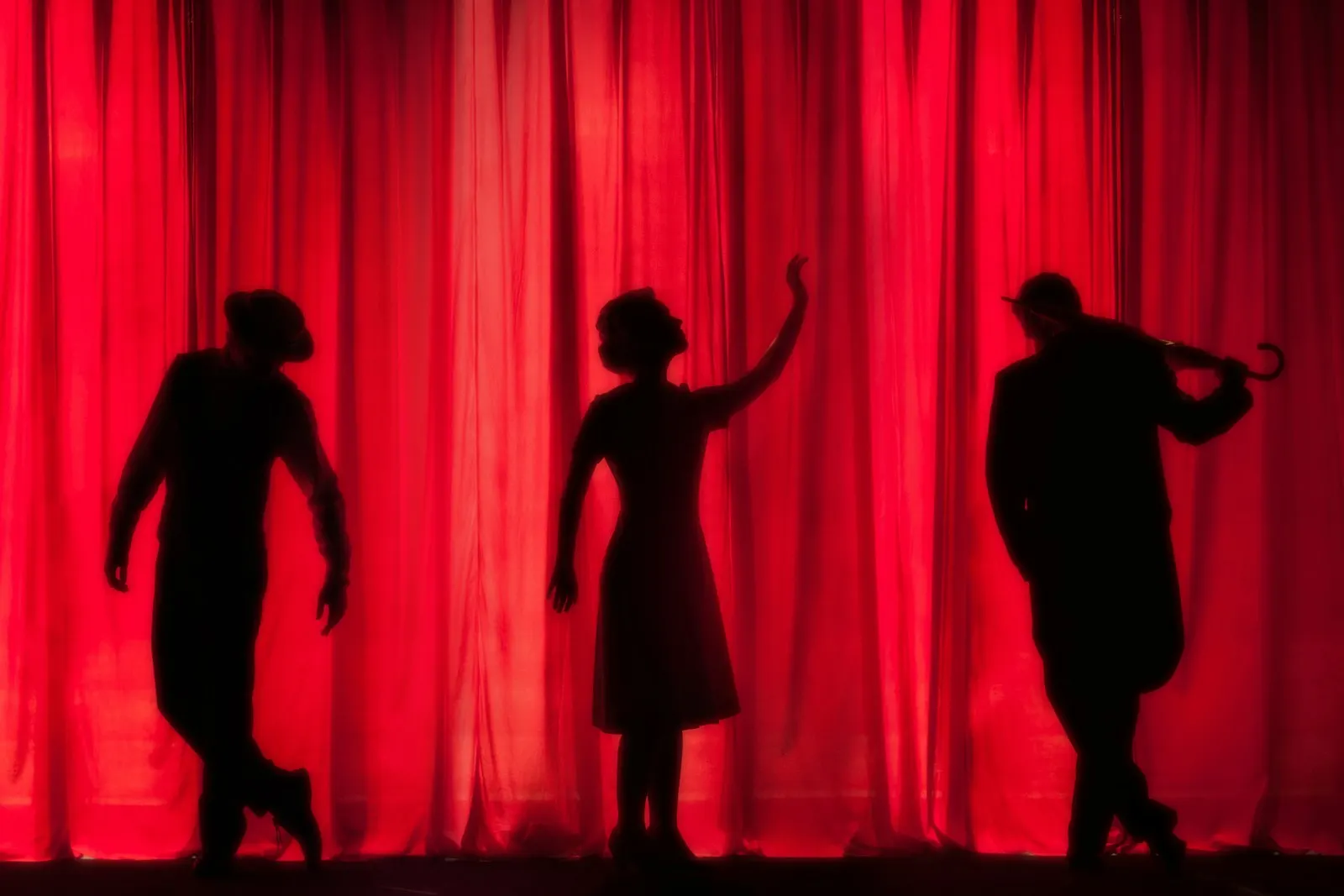Silhouettes d’artistes devant un rideau rouge